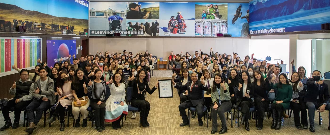 Participants gathered in a hall in front of a “Leaving No One Behind” screen