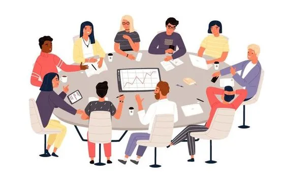 This may contain: group of people sitting around a round table with papers and laptops on it, talking to each other